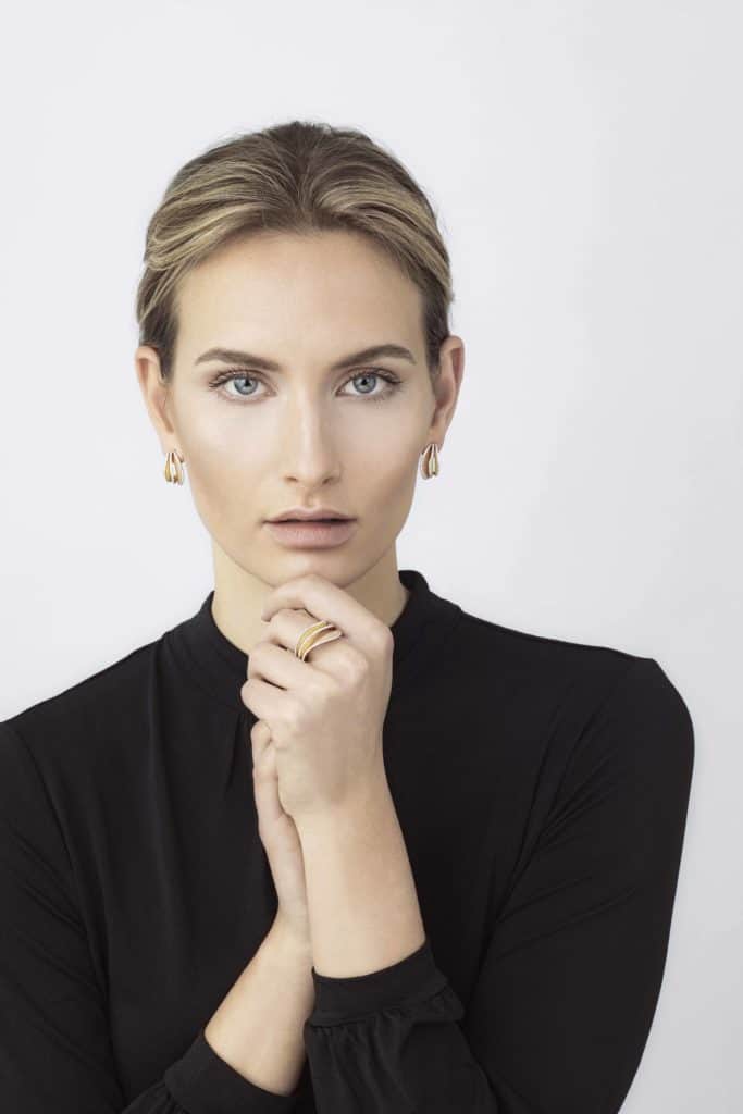 Femme portant des bijoux en or, portrait élégant pour Bijouterie Golaz.